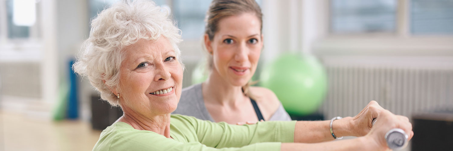 Caregiver helping elderly woman exercise